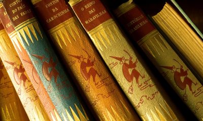 备考学生在图书馆专注翻阅教资综合素质教材，书桌整洁、橙色台灯营造温暖学习氛围，与中小学教师资格证考试网备考场景高度契合